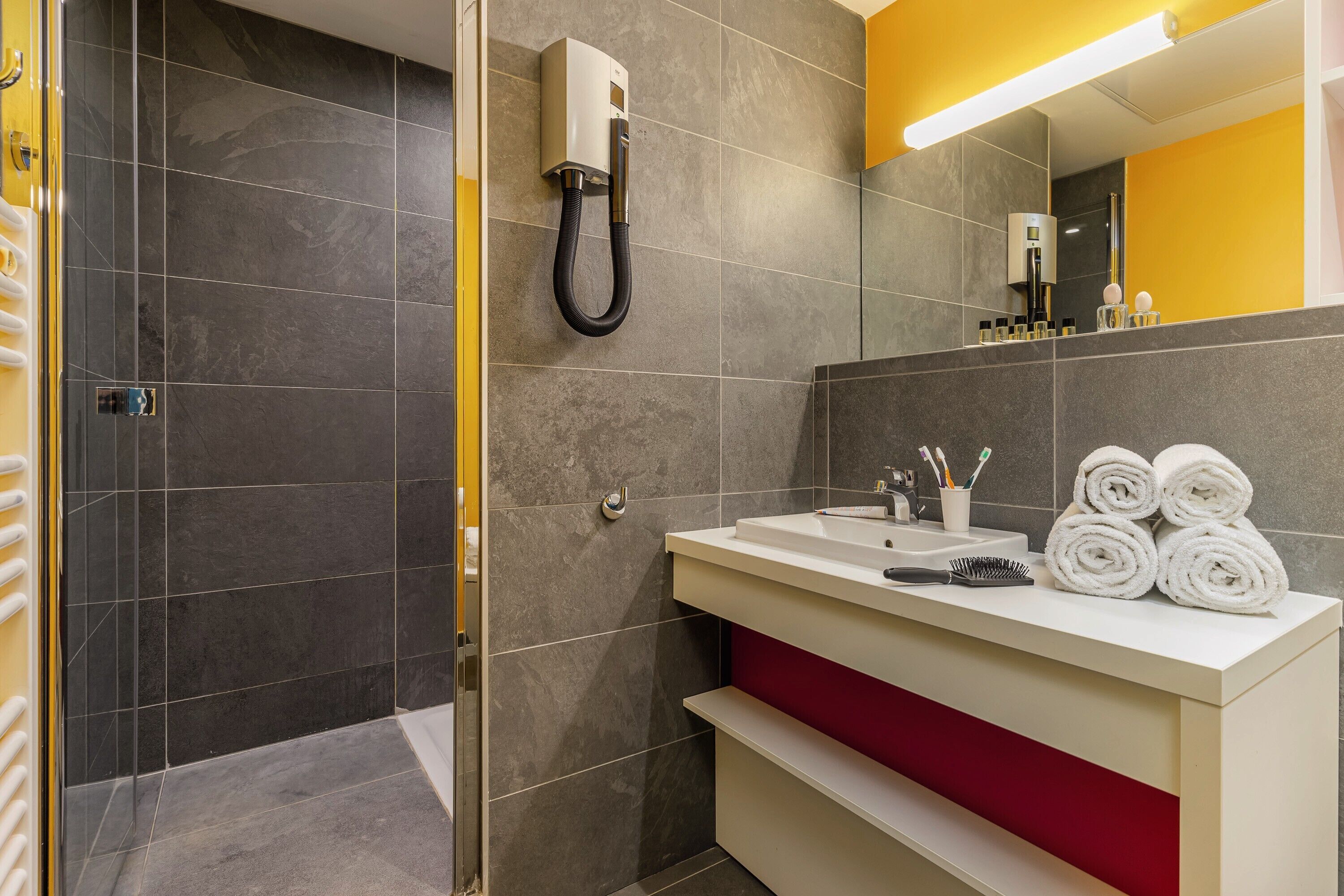 Un bagno moderno con doccia, lavandino e accessori da bagno, e uno specchio.