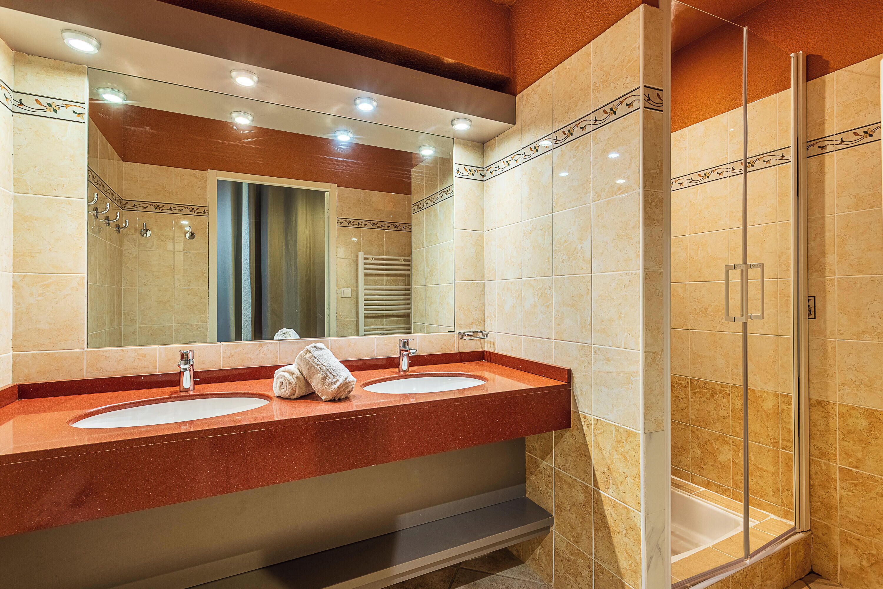 A bathroom with two sinks, a large mirror, and a glass shower enclosure.