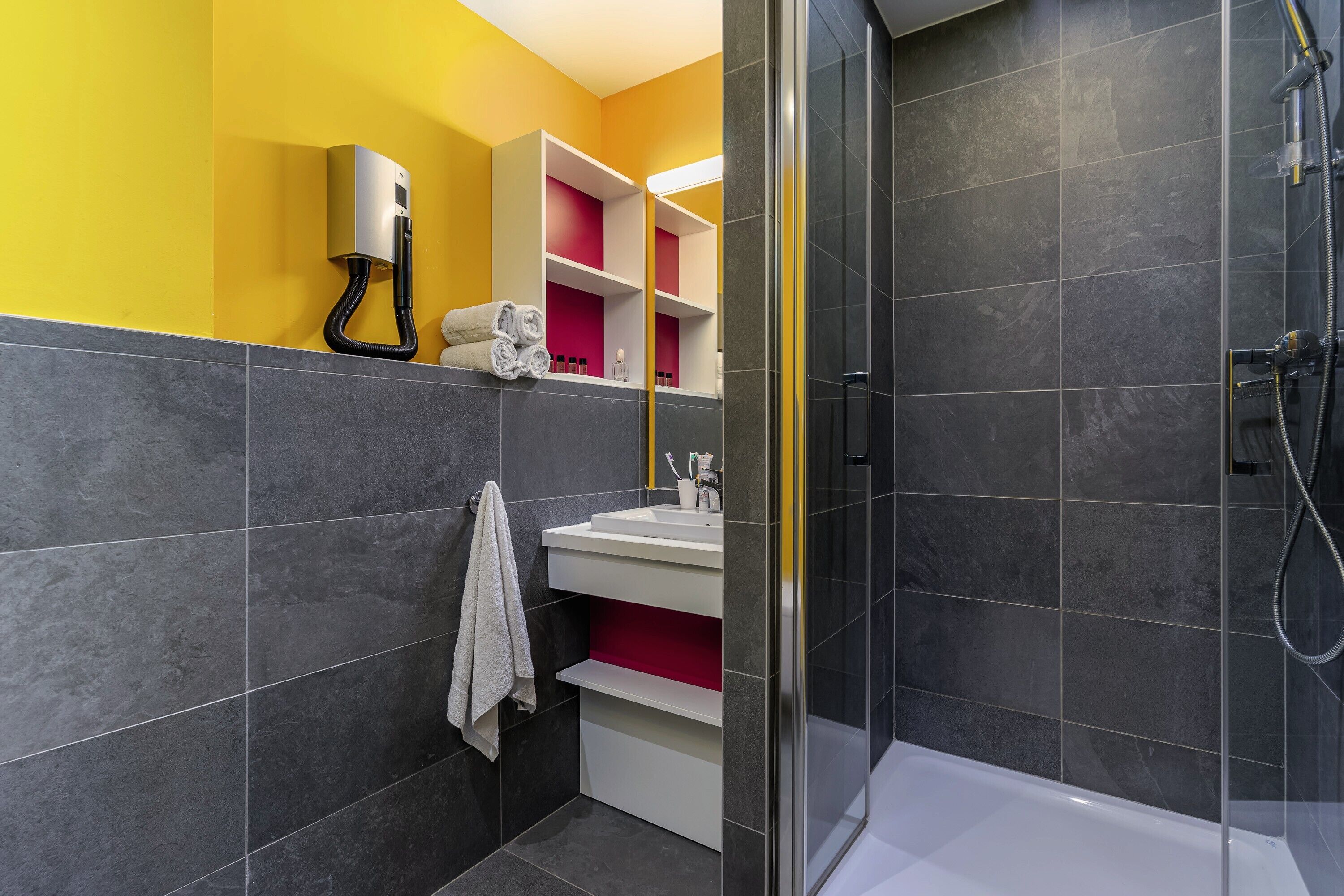 Ein modernes Badezimmer mit Duschkabine aus Glas, einem weißen Waschbecken und einem Handtuchhalter.