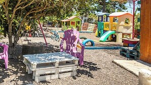 A playground with colorful play structures and a wooden bench.