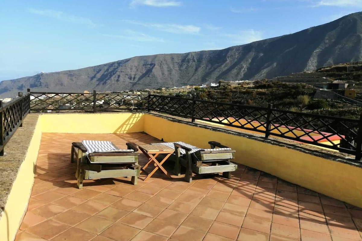 Une terrasse avec vue sur les montagnes, une table et des chaises.
