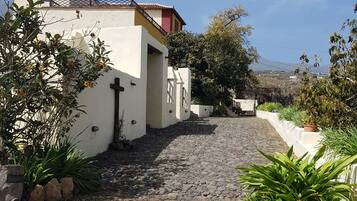 A cobblestone pathway leading to a white building with a red-tiled roof.