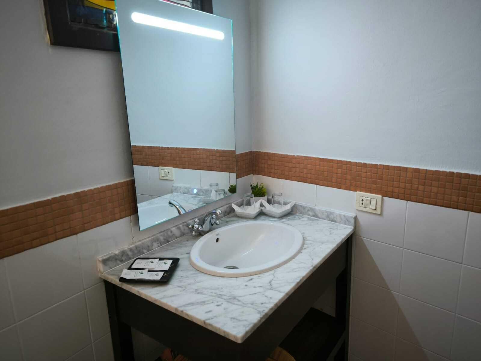 Un baño con lavamanos de mármol, espejo y salpicadero de azulejos.