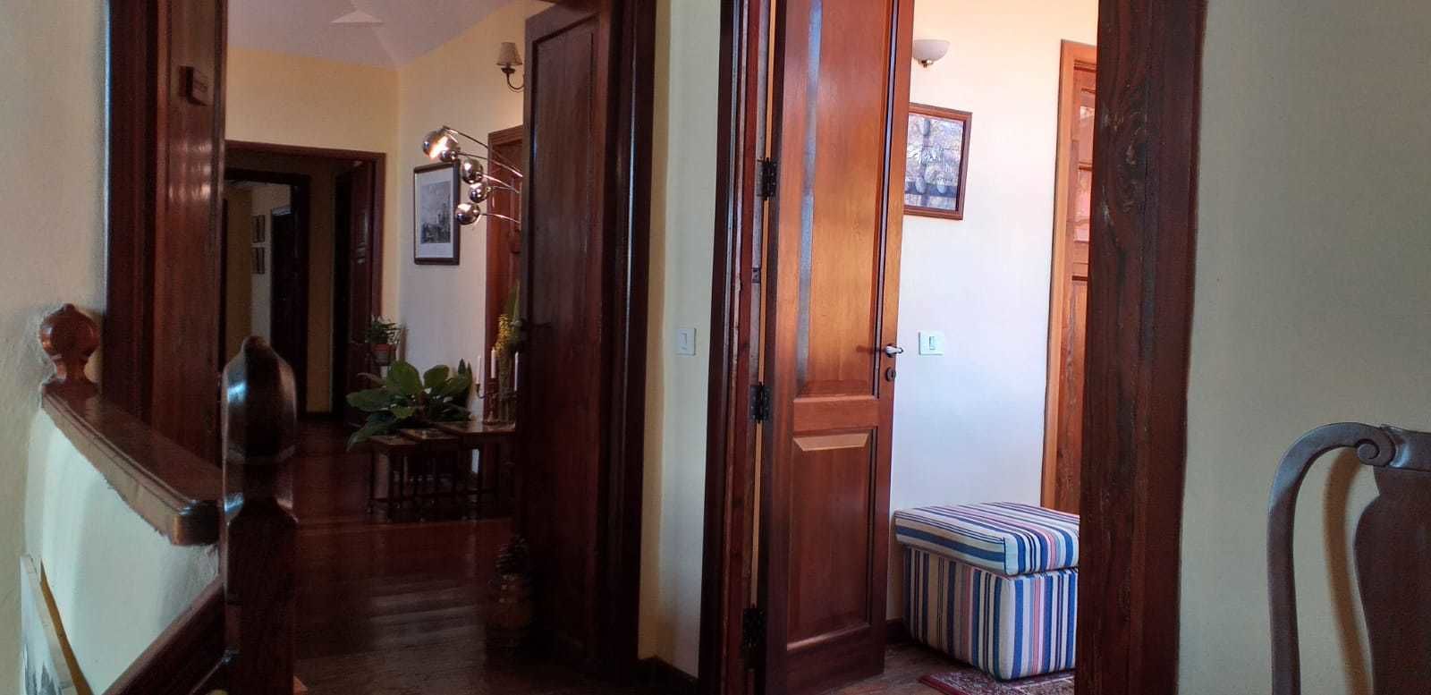 A wooden hallway with a bench, a door, and a wall-mounted light fixture.