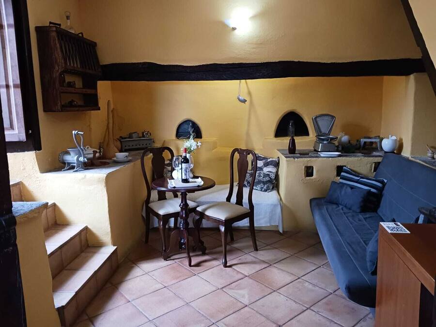Une pièce confortable comprenant une table à manger, deux chaises, un canapé, un coin cuisine avec une cuisinière et un petit escalier.