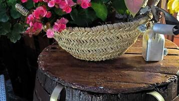 A rustic wooden barrel used as a planter with pink flowers and a woven basket.