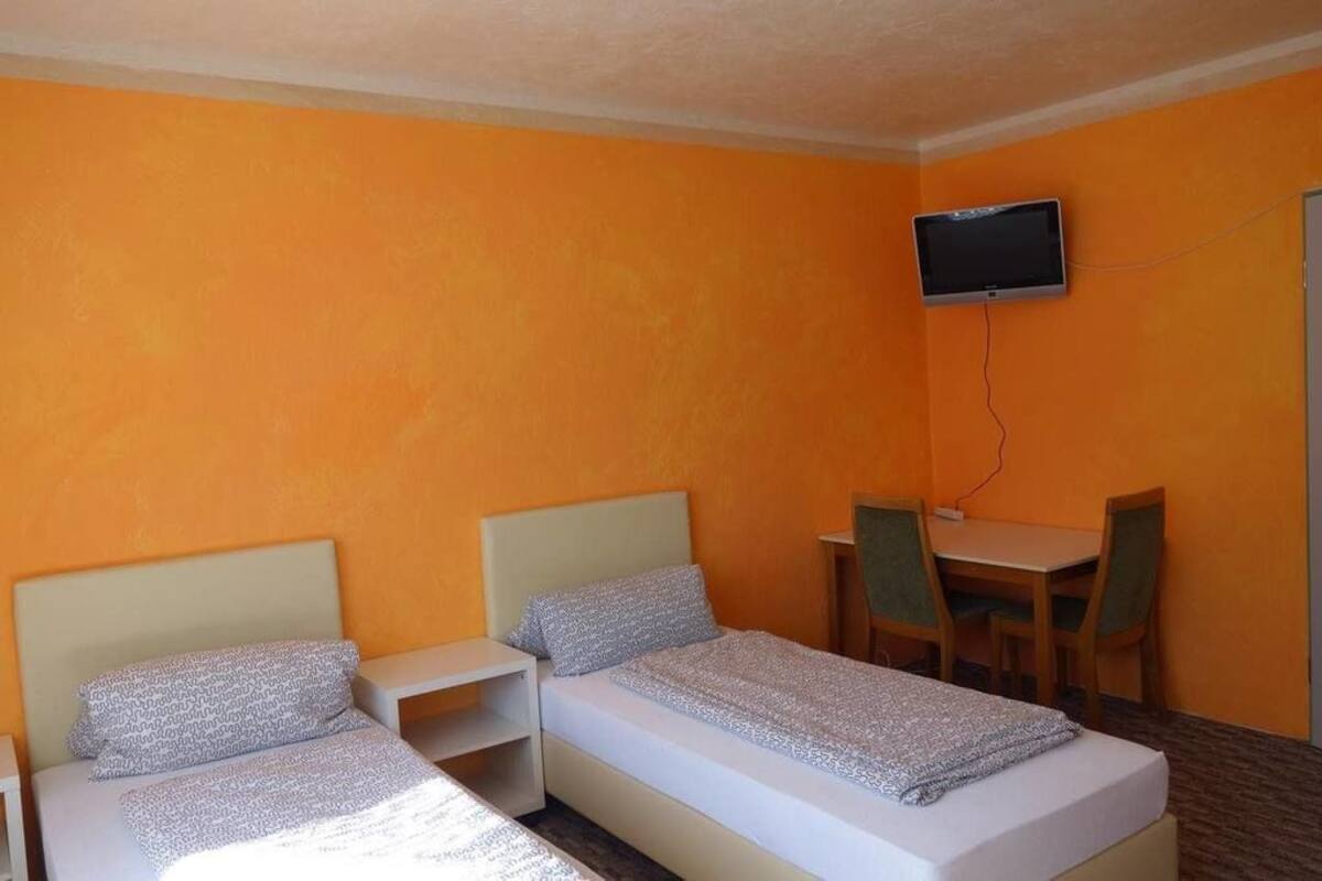 A hotel room with two beds, a desk, and a television.