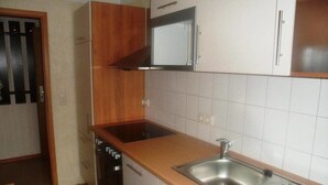 Une cuisine de taille réduite équipée d’une cuisinière, d’un four, d’un four à micro-ondes et d’un évier.