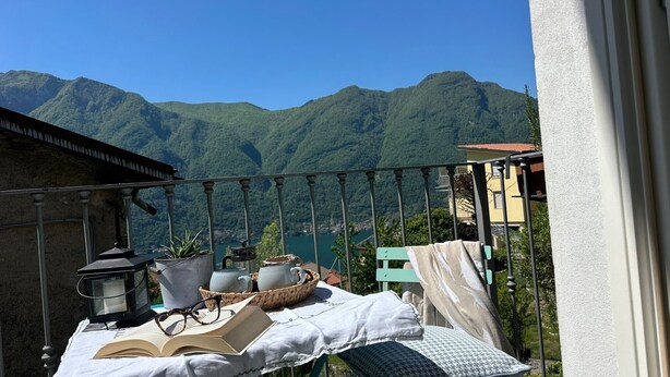 Ein Balkon mit Tisch, auf dem ein Buch, Gläser, eine Laterne und ein Korb mit Teekanne zum Lesen bereitstehen.