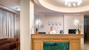 A reception area with a wooden counter, a large aquarium, and a sofa. - Arcadia Apartments (Odesa)