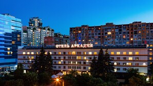 A hotel with multiple floors, a prominent sign, and a modern building in the background. - Arcadia Apartments (Odesa)