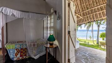 Relax in this serene retreat with a comfortable bed, a bedside table, and a door leading to an outdoor space with ocean views.