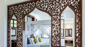 Une chambre à coucher avec un lit à baldaquin, des meubles en bois et un paravent décoratif.