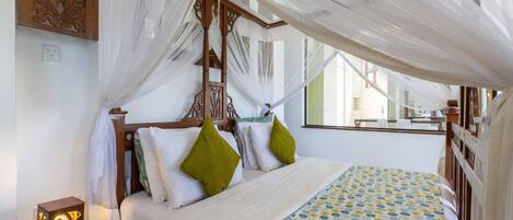 A bed with a canopy, a bedside table with a lamp, and a patterned bedspread.
