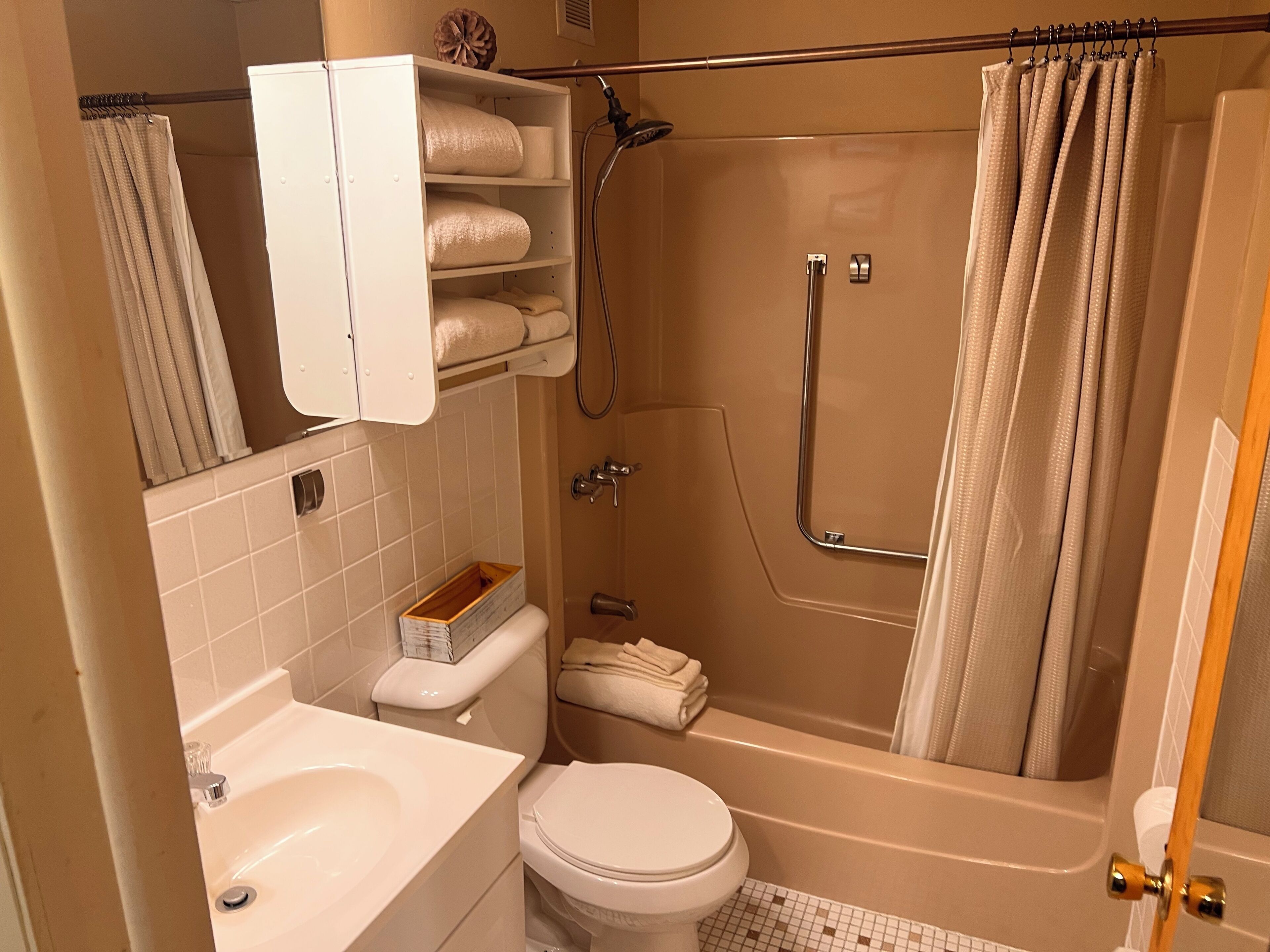 Een badkamer met een bad, toilet, wastafel en handdoekhouder.