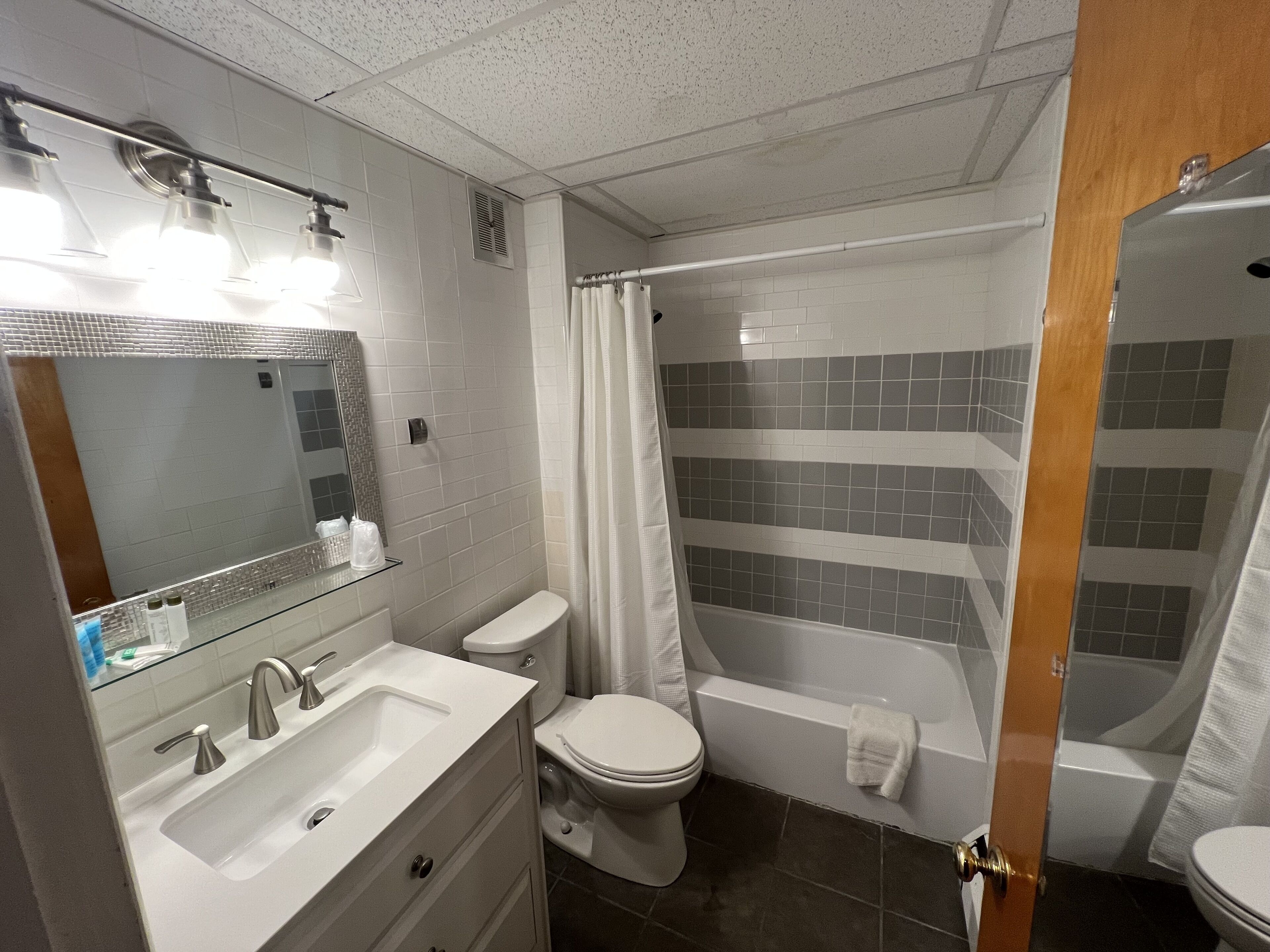 A modern bathroom with a shower, toilet, sink, and mirror.