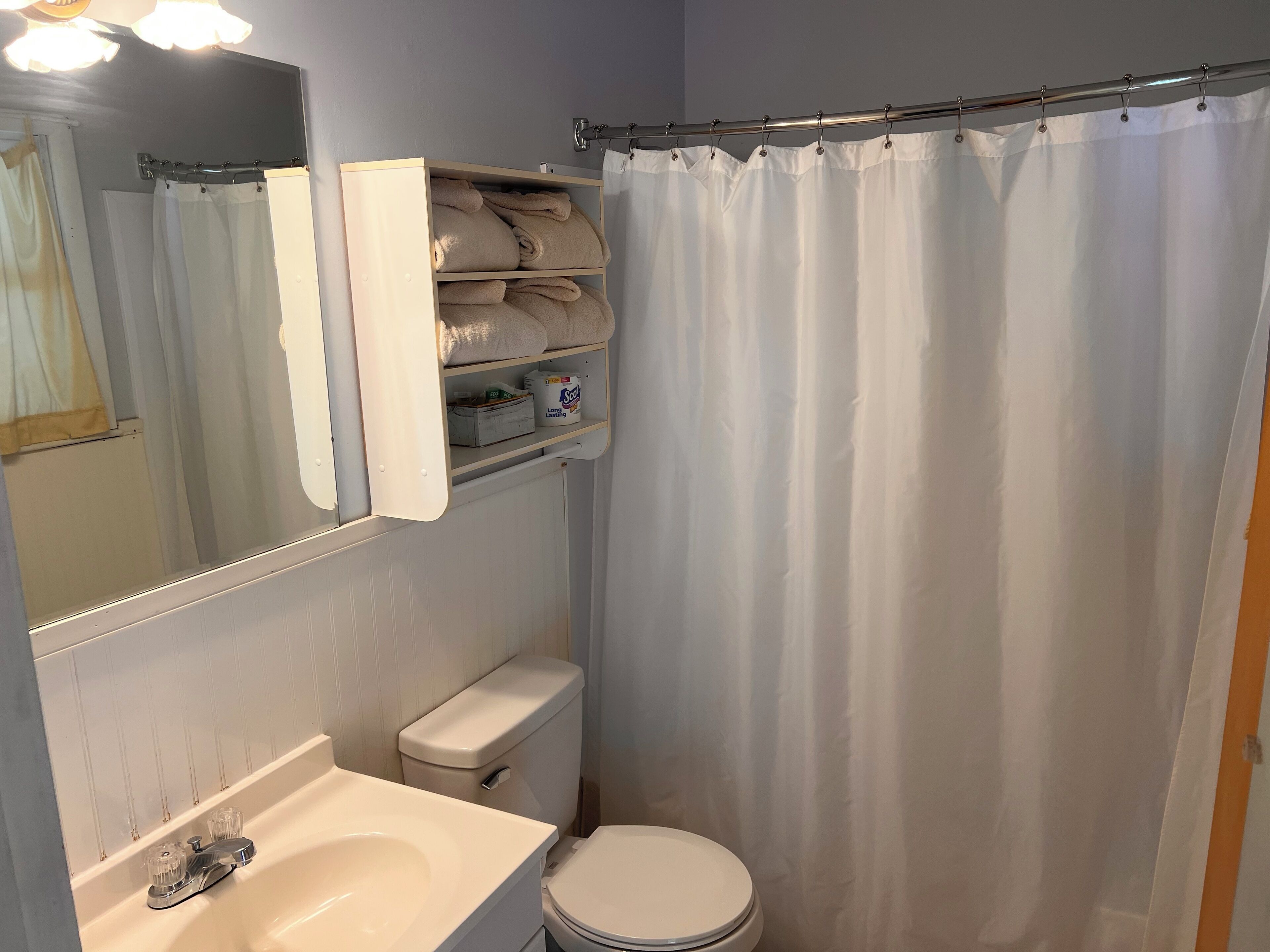 A bathroom with a white sink, toilet, and a shower curtain.