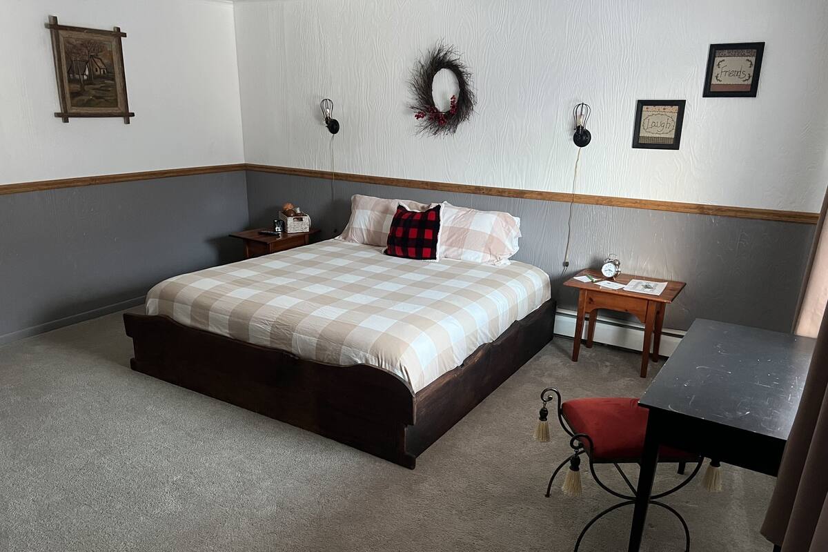 A bedroom with a bed, bedside table, and a desk with a chair.