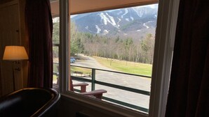 Une pièce dotée d’une grande fenêtre donnant sur un paysage montagneux, avec une petite table et une chaise.