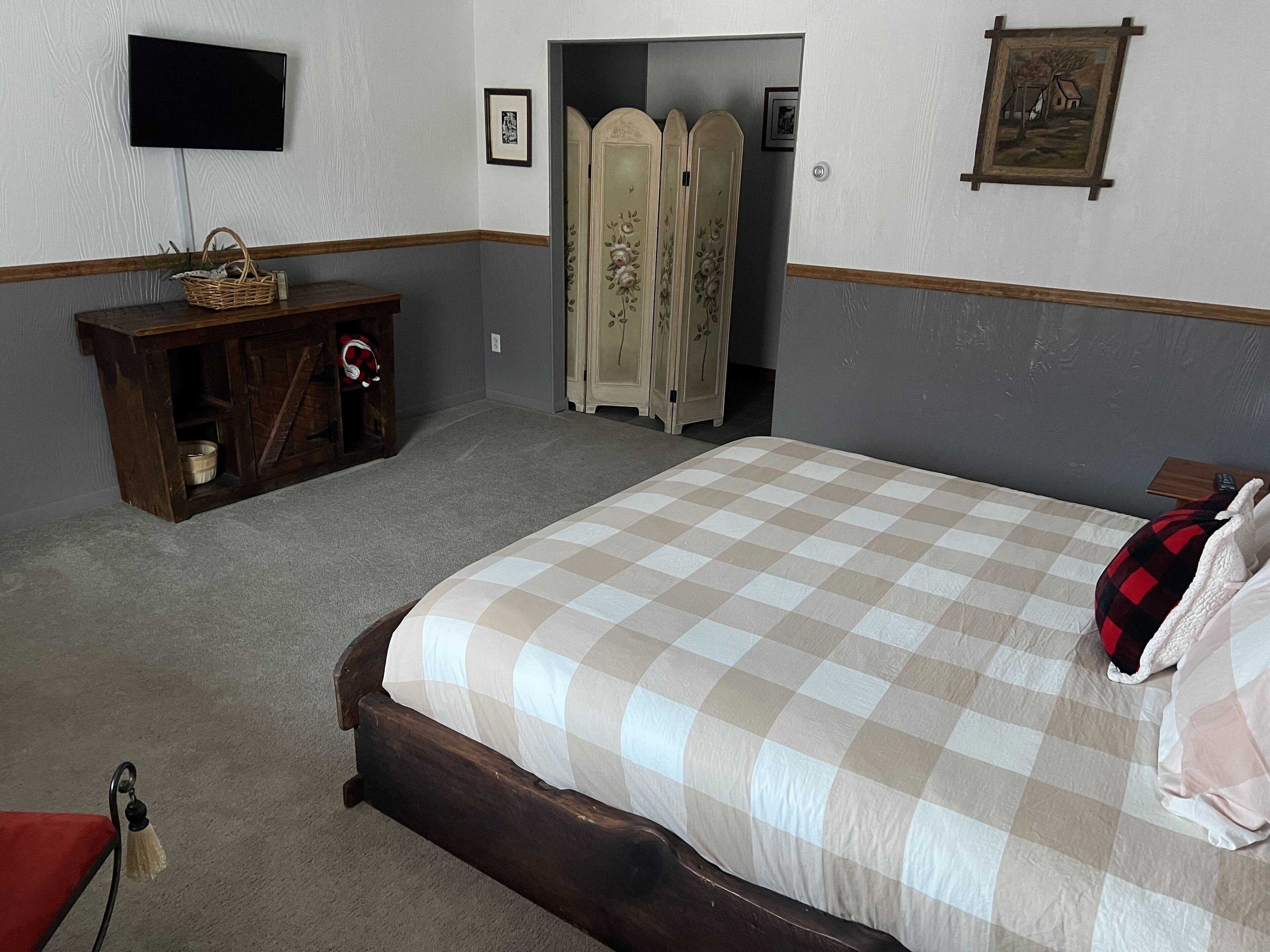 Un dormitorio con una cama grande, un aparador de madera, un televisor y un armario.