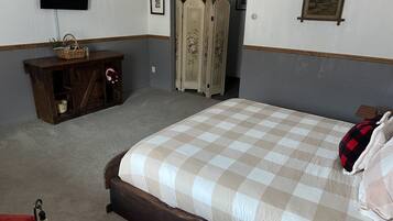 Un dormitorio con una cama grande, un aparador de madera, un televisor y un armario.