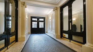 A hallway with a black door, white walls, and a tiled floor. - Paris Square (Paris)