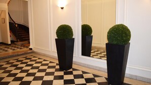 A checkered floor, a staircase, and two potted plants in a hallway. - Paris Square (Paris)