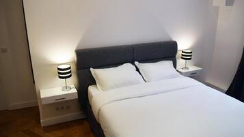 Un lit bien fait, avec du linge de lit blanc et deux tables de chevet avec des lampes.