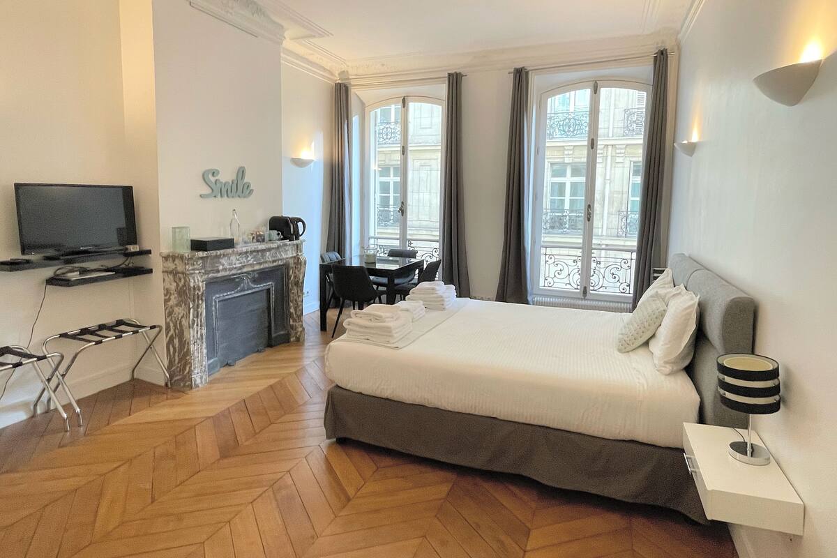 Ein Hotelzimmer mit Bett, Fernseher, Kamin, Essbereich und großen Fenstern.