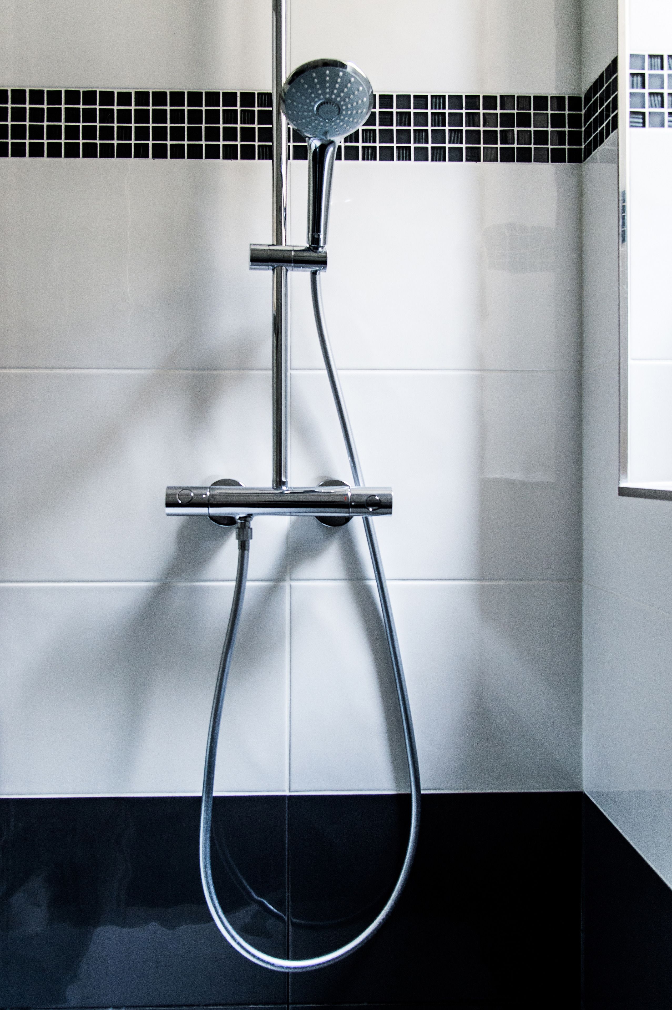Een moderne douche met een handdouche en een vastgeplaatste douchekop, bevestigd aan een chroomdoucheset.