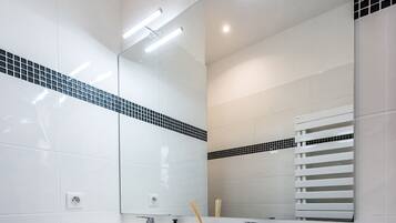 A modern bathroom with a white sink, mirror, and towel storage.