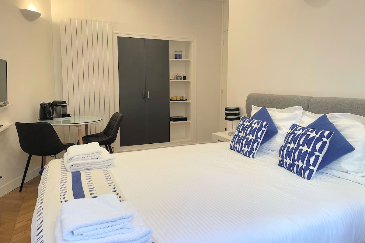 Ein Hotelzimmer mit Bett, Schreibtisch mit Stuhl, Kleiderschrank und Fernseher.