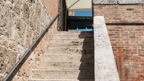 A set of stone steps leading up to a brick wall with a white umbrella. - L'Albero di Gameli (Chiusi)