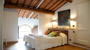 A bedroom with a wooden ceiling, a bed with a white bedspread, multiple pillows, and two bedside lamps. - L'Albero di Gameli (Chiusi)