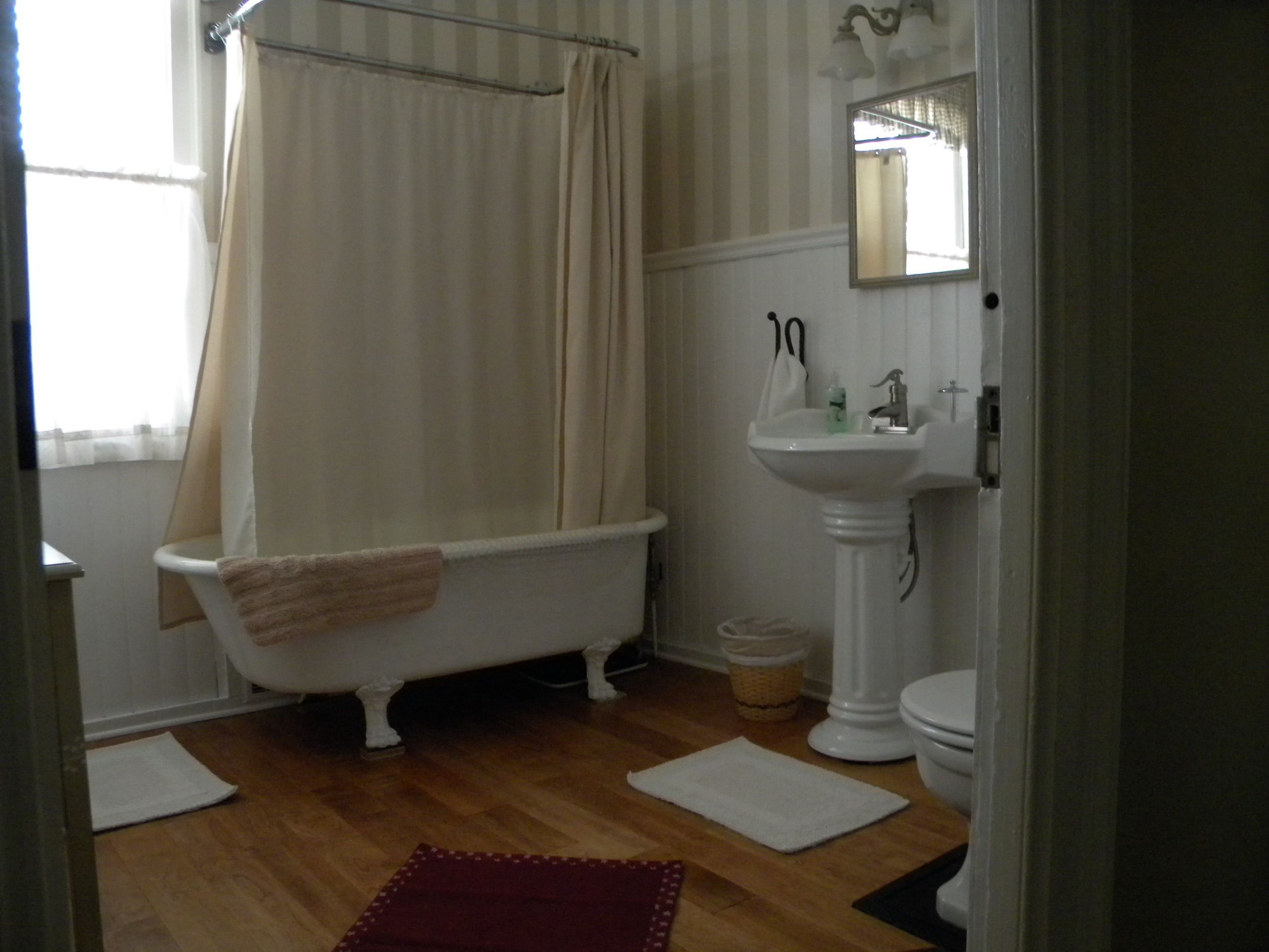 A bathroom with a clawfoot bathtub, a pedestal sink, and a toilet.