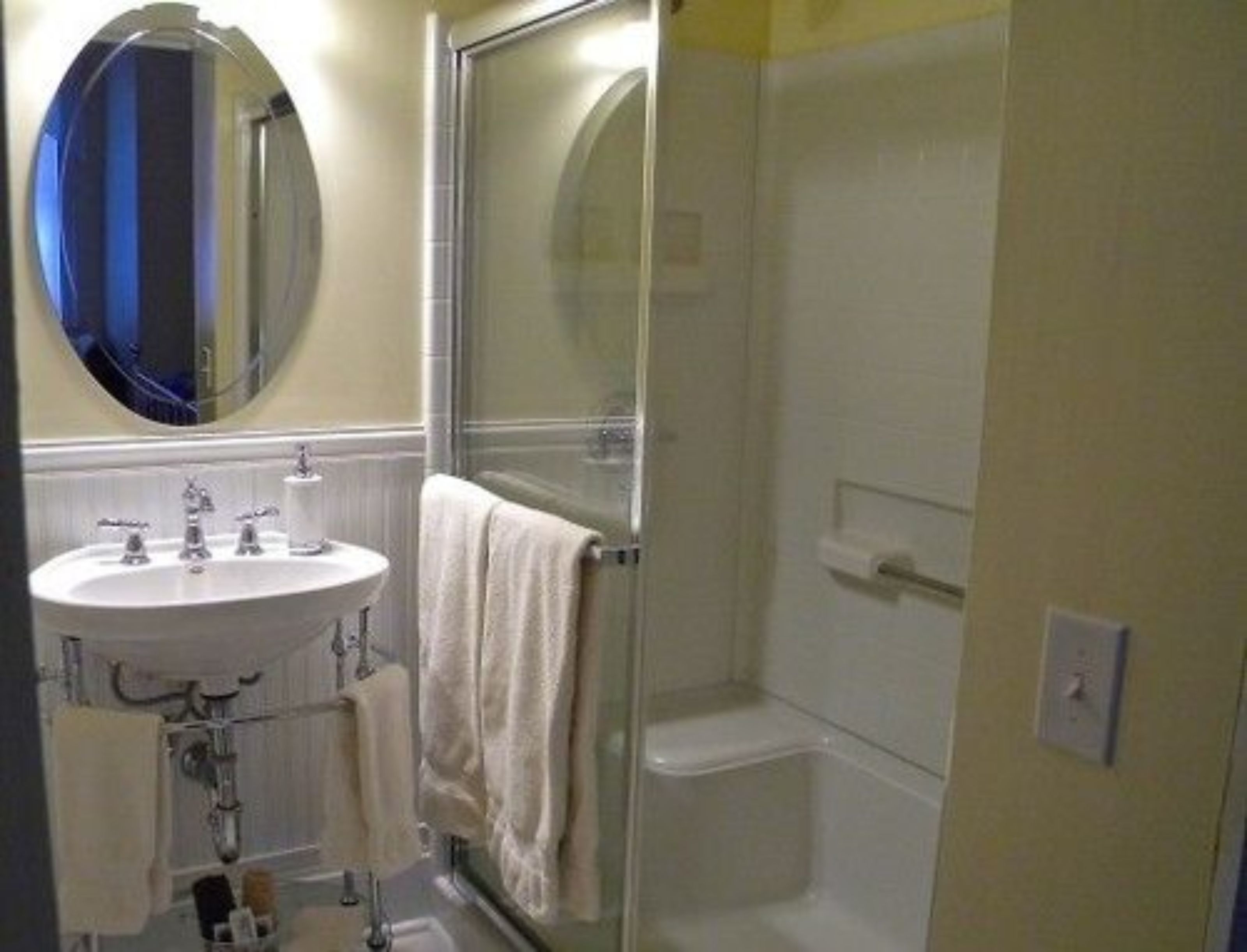 A bathroom with a sink, mirror, and shower.