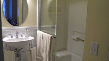 A bathroom with a sink, mirror, and shower.