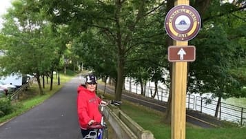 A person on a bicycle next to a sign for the Canalway Trail.