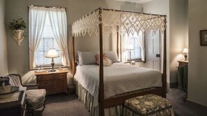 A four-poster bed with a canopy, a bedside table with a lamp, a chair, and a small table with a lamp. - B&B at Oliver Phelps (Canandaigua)