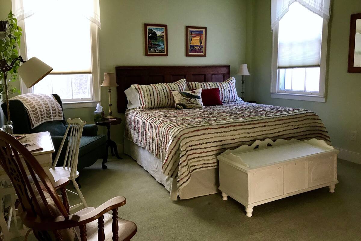A bedroom with a bed, bedside tables, a chair, and a window.
