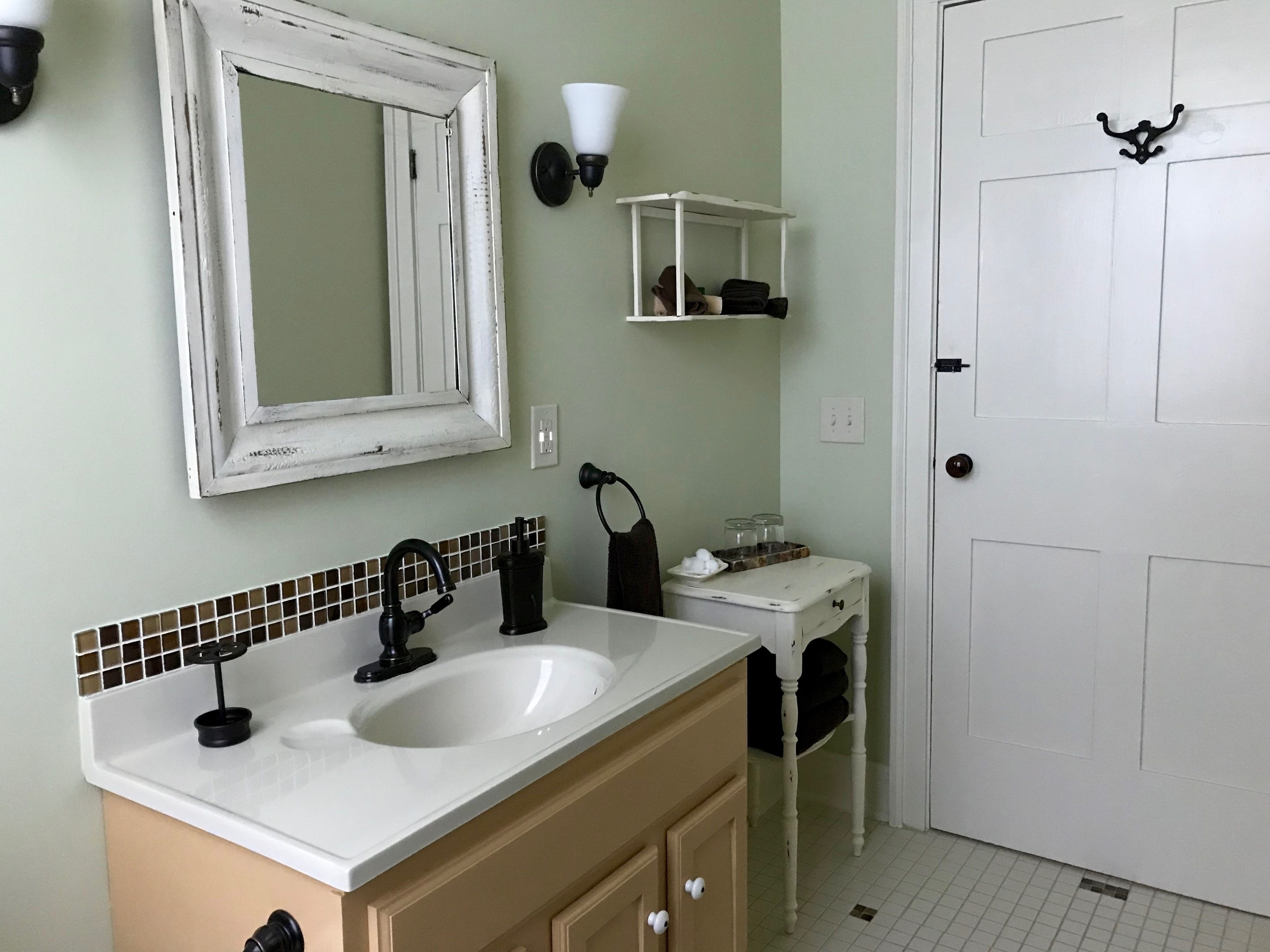 Un baño con lavamanos blanco, un espejo, toallero y una puerta.