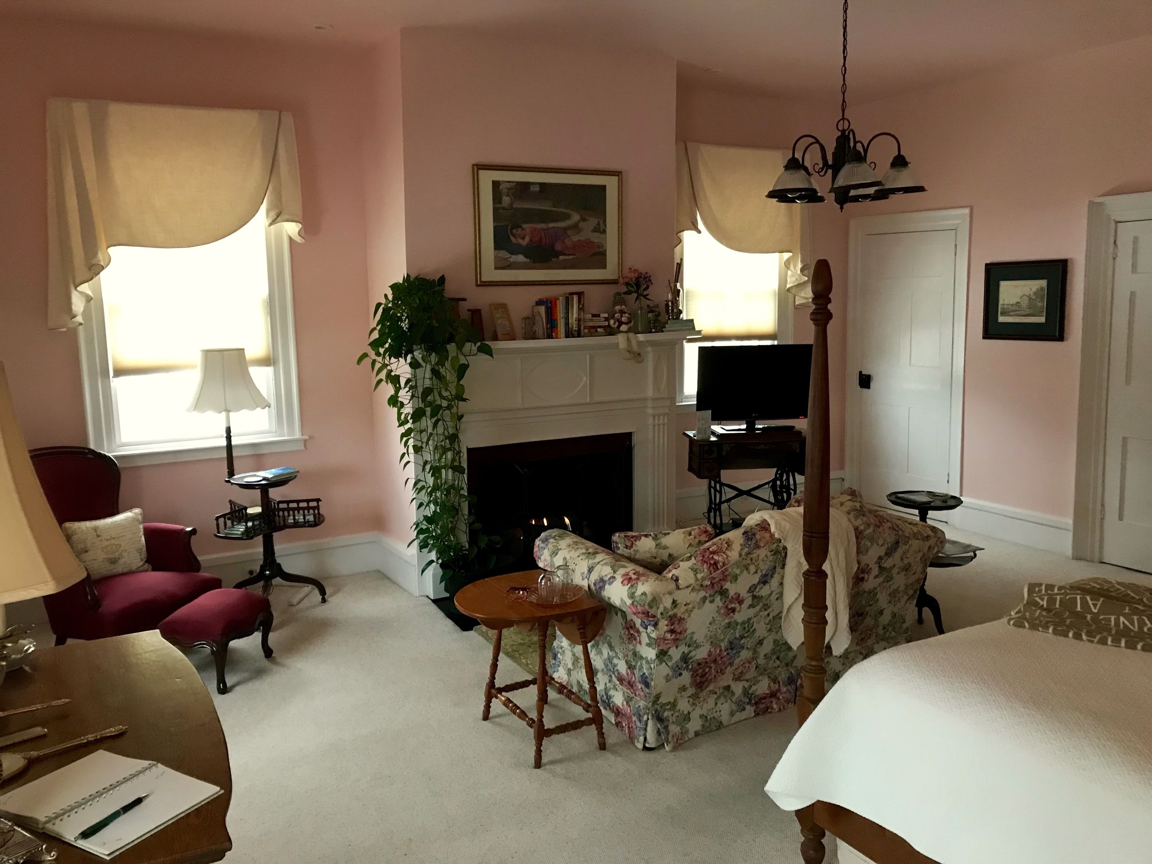 A cozy living room with a fireplace, a comfortable sofa, a dining table, and a chair.