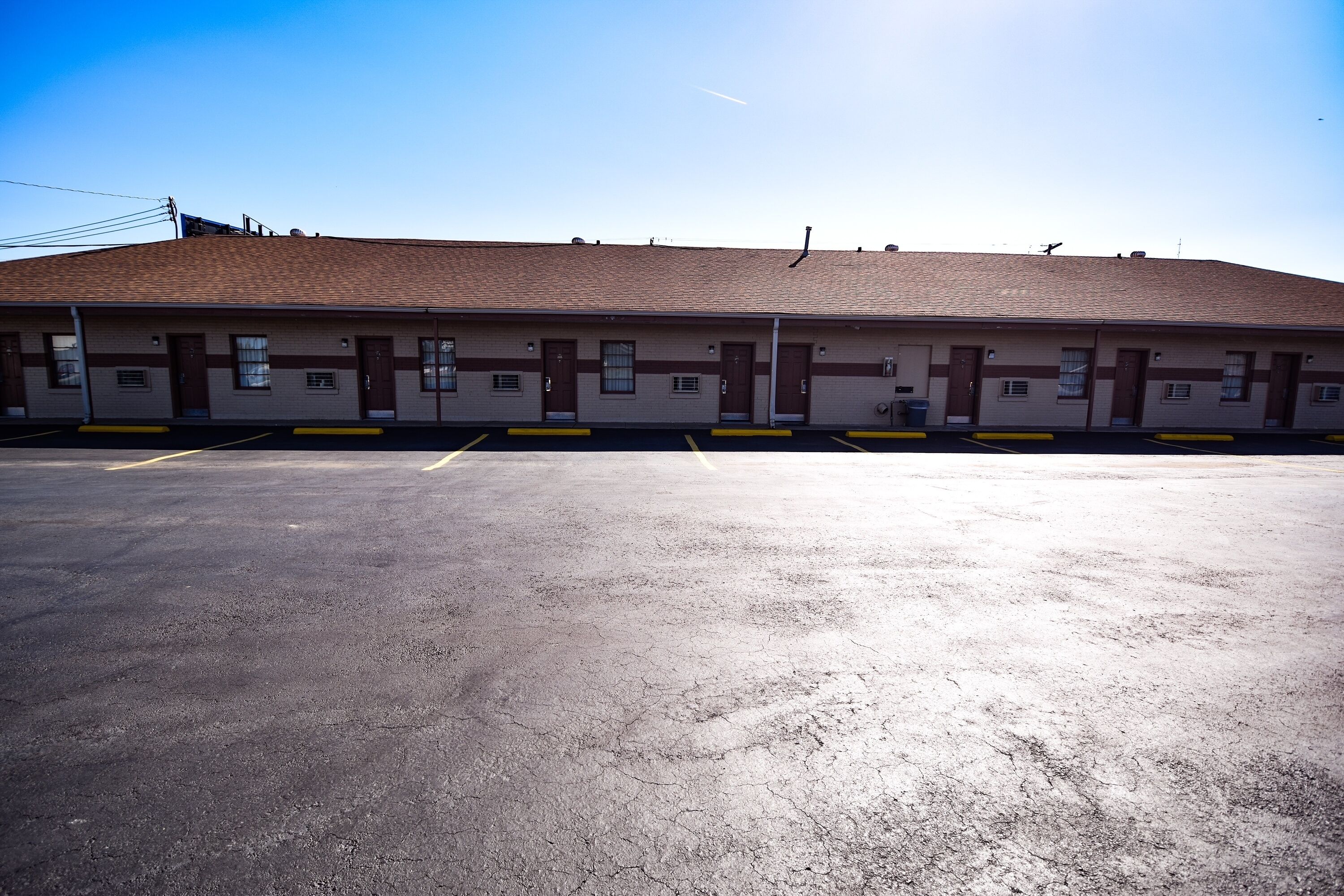A building with a flat roof, multiple doors, and a parking lot.