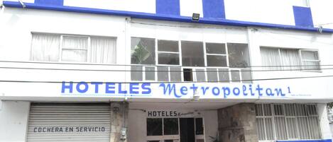Un hotel llamado 'HOTELES Metropolitan' con una persiana bajada a la izquierda y una entrada abierta.