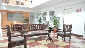 A waiting area with a checkered floor, wooden furniture, and potted plants.