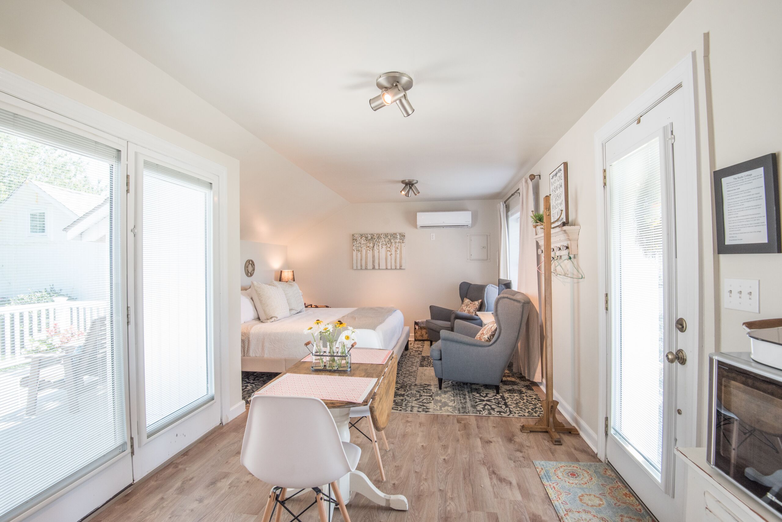 Une chambre confortable avec un lit, une table de chevet et un petit bureau avec une chaise. On y trouve une fenêtre avec des stores, un ventilateur de plafond et une cheminée.