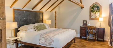 A bedroom with a wooden bed, bedside tables, a desk, and a chair.