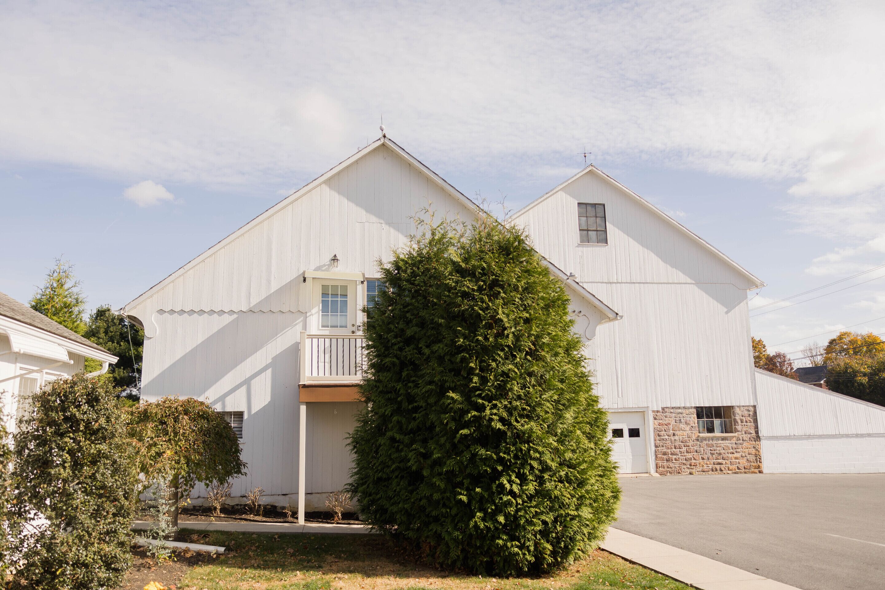 A two-story white building with a large front porch and a stone foundation.