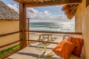 A beachside balcony with a table set for two, overlooking the ocean.