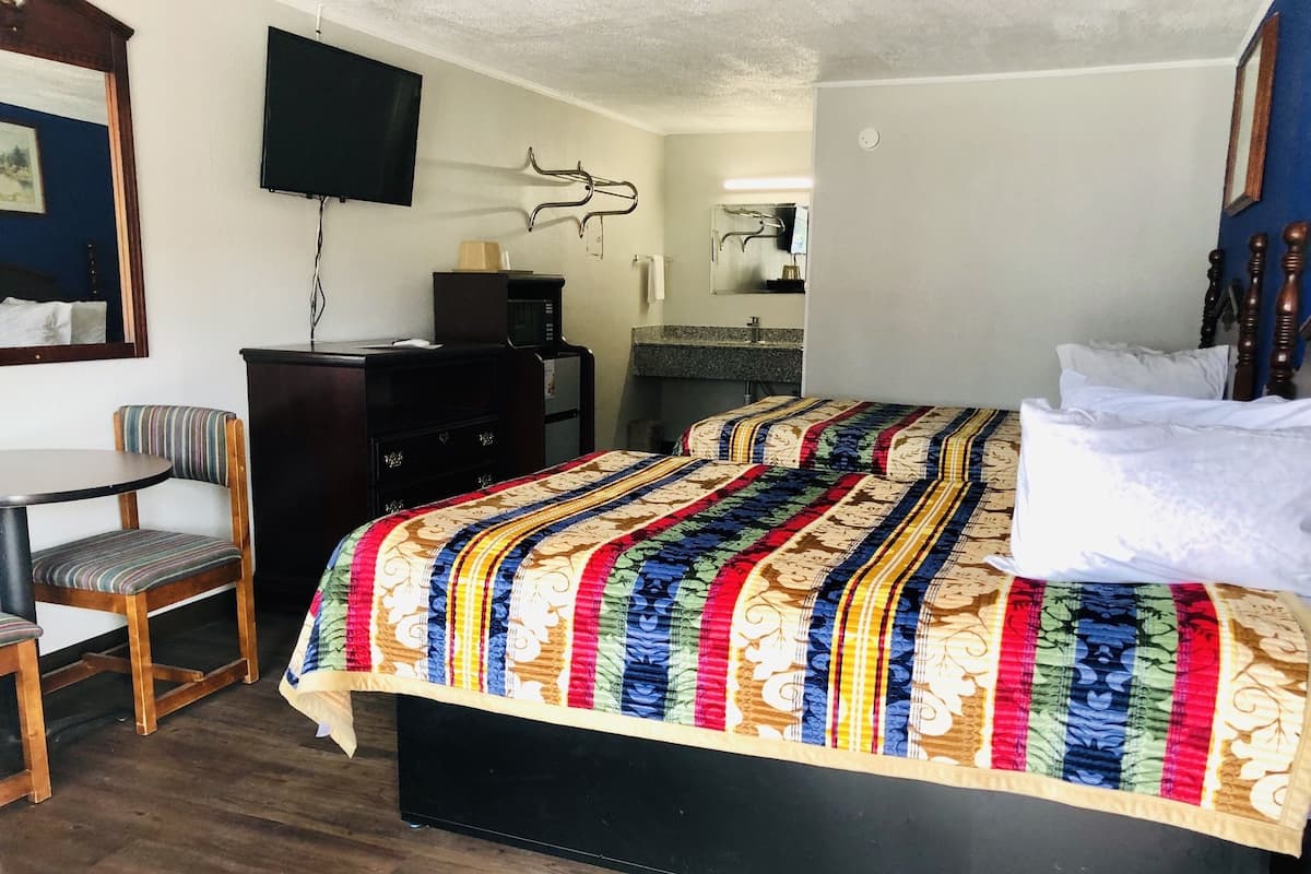 A hotel room with a bed, a desk, a chair, a television, and a bathroom.
